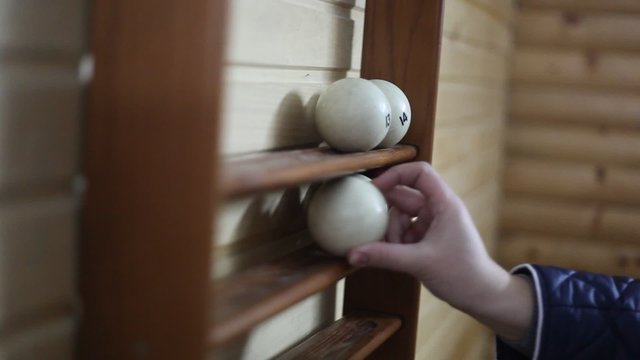 he puts the white billiard balls on the shelf for the balls attached to a wooden wall. Video. HD quality. 1920x1080