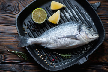 Cast-iron grill with fresh uncooked dorado, studio shot