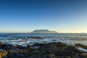 Cape Town Table Mountain's iconic flat top seen from Blouberg Strand in South Africa during sunset.