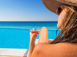 woman with a hat is relaxing in an infinity pool