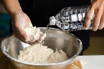 Pouring water into the bowl for mixing dough,bread cooking