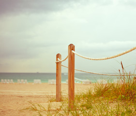 Naklejka premium Path on the sand going to the ocean in Miami Beach Florida at sunrise or sunset, beautiful nature landscape, retro instagram filter and shallow focus for vintage looks