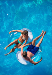 Couple relaxing on a lilo mattress at the swimming pool