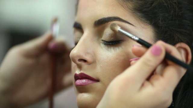 A pretty woman having make-up applied by a makeup artist. 