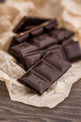 Dark Chocolate Bars on Crumbled Paper and Wooden Table