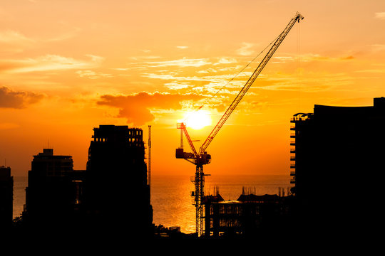 silhouette of construction site crane with sunset on the sea