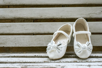 Baby girl shoes on wooden background, vintage color tone.