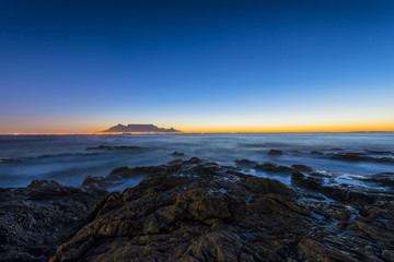 Cape Town Table Mountain's iconic flat top seen from Blouberg Strand in South Africa during sunset.