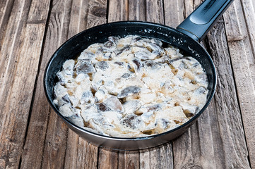 Fried mushrooms pan on wooden background