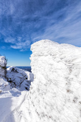 Fototapeta na wymiar Rock plastered with snow. Winter forest landscape