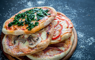 Mini pizzas with various toppings on the wooden board