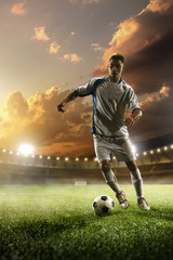 Obraz na płótnie Canvas Soccer player in action on sunset stadium background