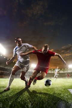 Fototapeta Soccer players in action on sunset stadium background 