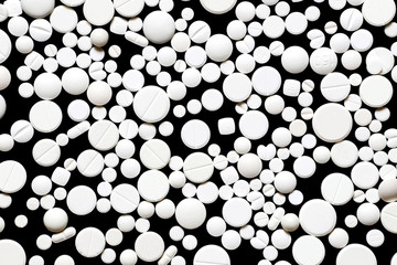 Scattering of white pills on black background