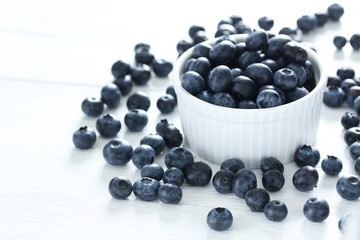 Blueberries in bowl on a white wooden background