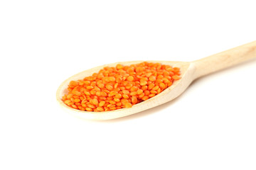 Red lentils in the wooden spoon on a white background