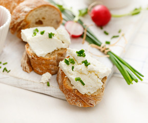 Canapes with curd cheese and fresh chive on a white table. Delicious and healthy breakfast