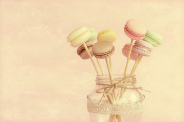 Colorful macaroons on wooden sticks in a glass jar