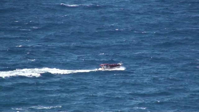 A small boat travels in the wild sea.