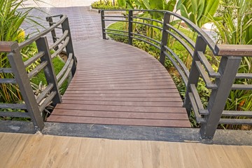 Sloping wooden boardwalk viewed as walking in garden
