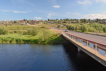 Fototapeta premium Rural area in the town of Mirny, Irelyakh bridge over the river.