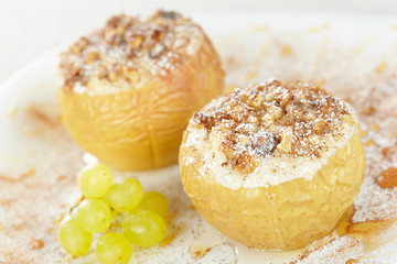 Apples baked with cottage cheese and raisins, decorated with nuts, cinnamon and powdered sugar