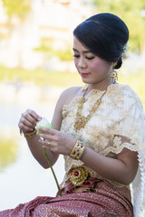 Beautiful Thai girl in Thai traditional costume trying to  roll lup lotus