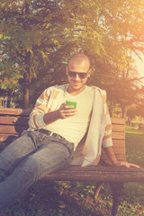 Obraz premium Urban guy texting on a bench in the park.