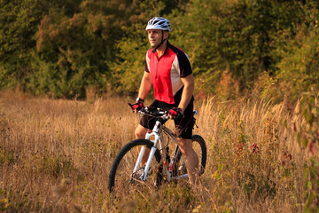 Cyclist with His Bike on the Autumn Meadow