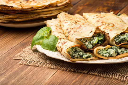Pancakes filled  with spinach and cheese  on the wooden surface.