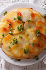 French food: Potato gratin on white plate closeup. vertical top view
