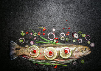 Whole Trout with herbs, spices and seasoning for fish dishes cooking on dark background, top view,...