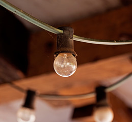 Light bulb on cable against brick wall