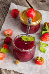 strawberry jam in a glass jar on a wooden table