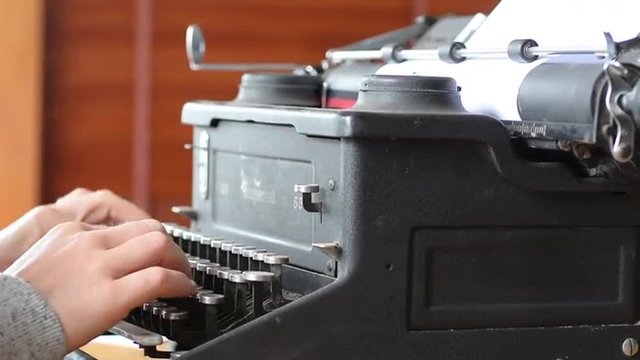 Hand of a young woman writer writing on antique typewriter.Type Writing Concept