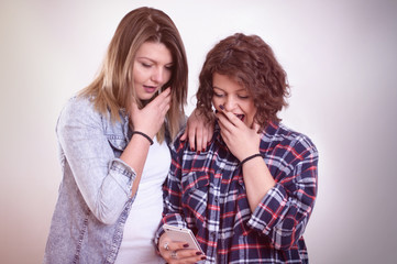 Two girls shocked staring at smartphone