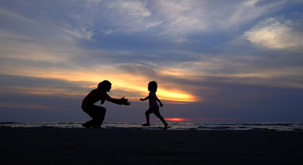 Silhouettes of mother and daughter at the beach.