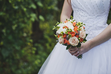 A bouquet of orange and pink flowers in the hands of the bride 4