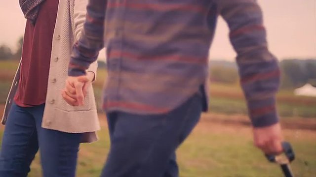 A couple walking and holding hands while pulling a wagon at a pumpkin patch