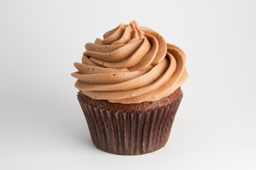 A chocolate cupcake with swirled frosting on a white background. - Powered by Adobe