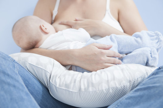 Mother feeding breast with nursing pillow