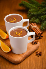 Hot chocolate with orange and spices on the rustic wooden table. Christmas composition. Selective focus.