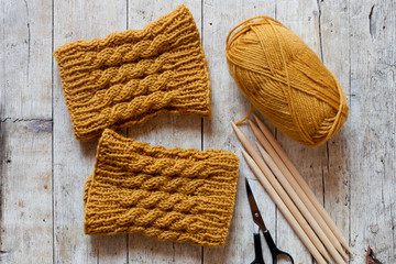 wool yellow legwarmers, scissors, knitting needles and yarn