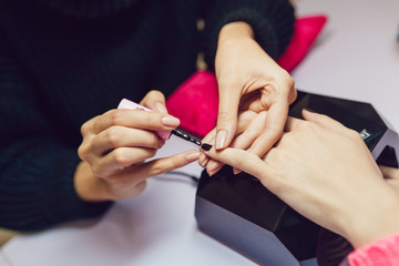 Obraz na płótnie Canvas Manicure. Beauty saloon. Close-up. Apply black nail polish.