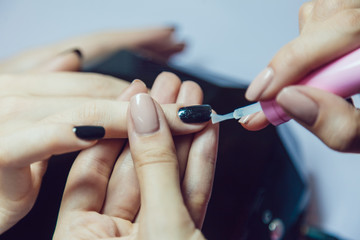 Manicure. Beauty saloon. Close-up. Apply black nail polish.