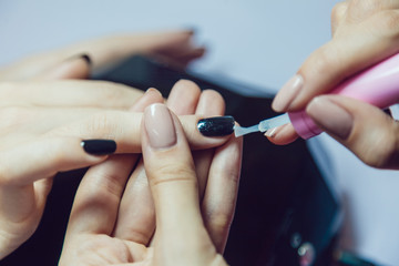 Manicure. Beauty saloon. Close-up. Apply black nail polish.