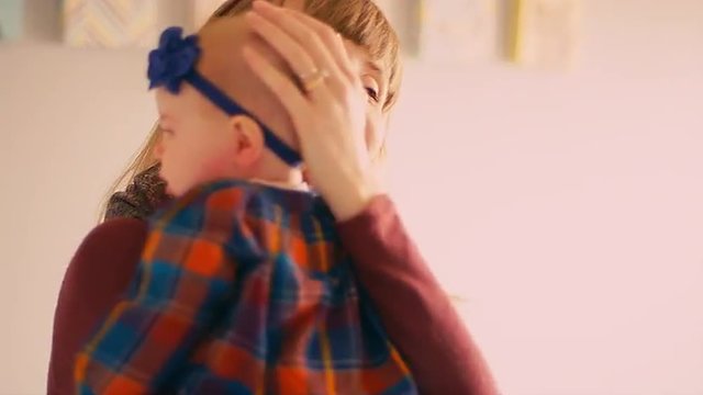 A mother picks her crying baby girl up out of her crib and starts bouncing her