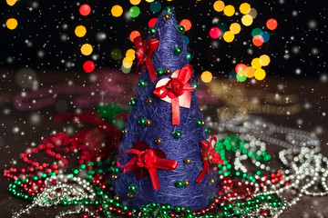 Beautiful violet handmade Christmas tree with decorations. Christmas lights background. Closeup. Selective focus
