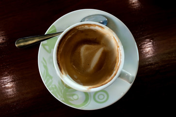 Cup of coffee with hot tea pot on wooden in over dark tone