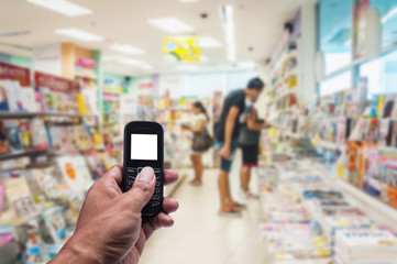 Fototapeta na wymiar Phone white screen in hand on blurred book store